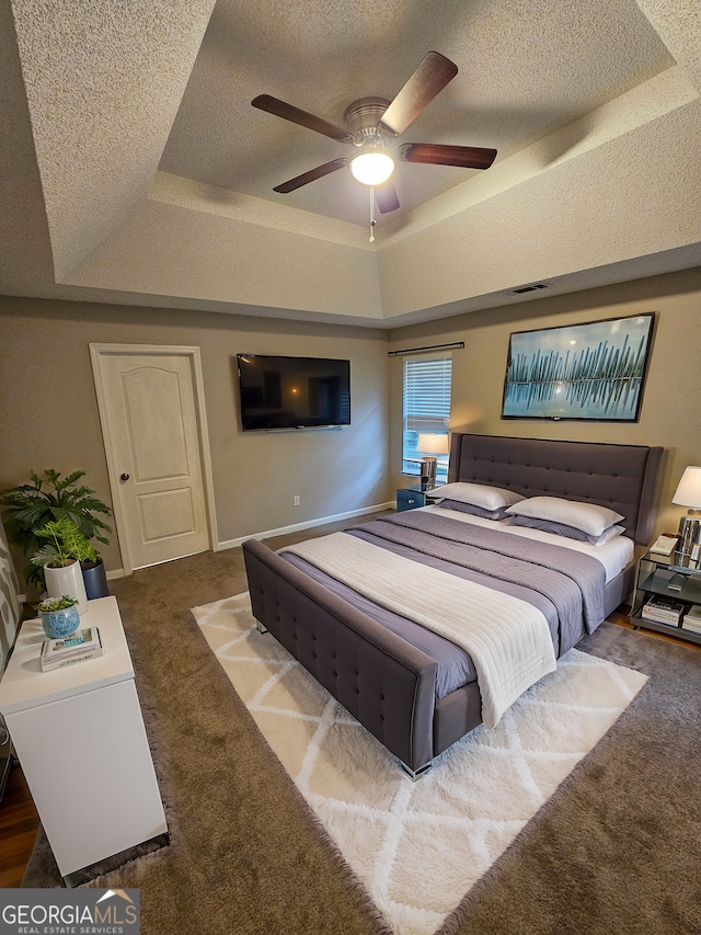 bedroom with a tray ceiling, visible vents, and a textured ceiling