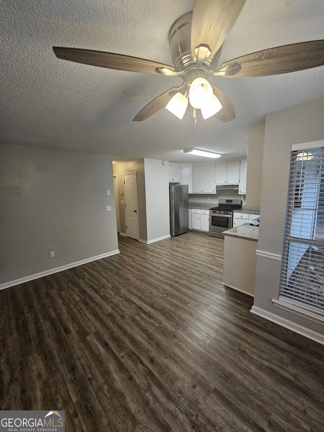 kitchen with under cabinet range hood, open floor plan, appliances with stainless steel finishes, dark wood-style floors, and a textured ceiling