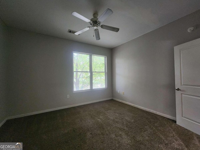 empty room with ceiling fan and dark colored carpet