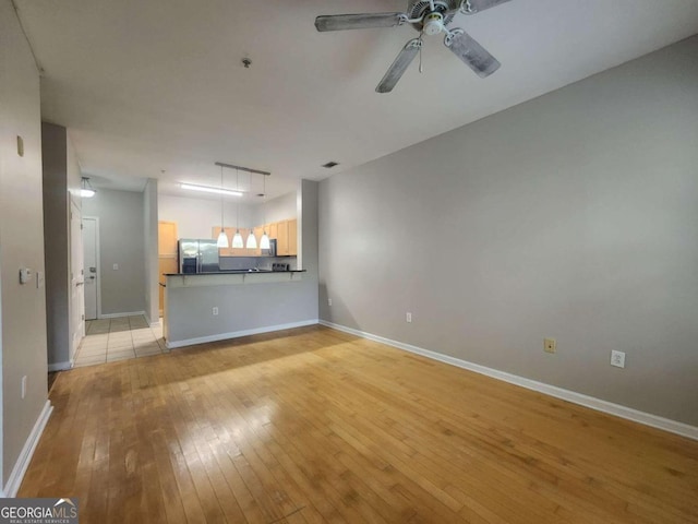 unfurnished living room featuring ceiling fan and light wood-type flooring