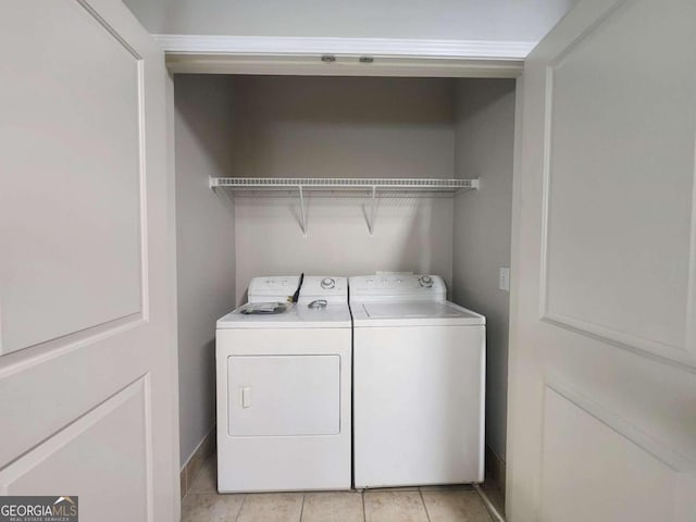 laundry area with washer and clothes dryer and light tile patterned floors