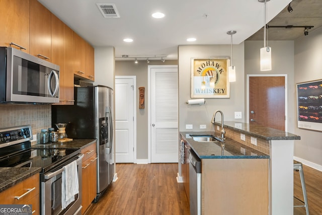 kitchen with sink, hanging light fixtures, a breakfast bar, appliances with stainless steel finishes, and light wood-type flooring