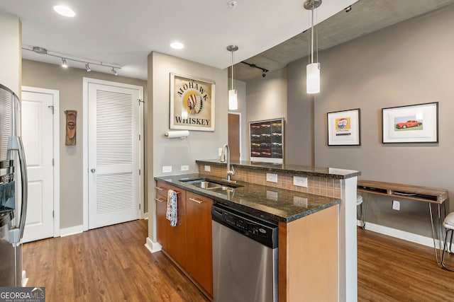 kitchen featuring dark stone counters, sink, decorative light fixtures, dishwasher, and dark hardwood / wood-style floors