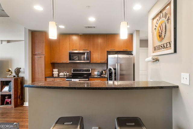 kitchen featuring decorative backsplash, pendant lighting, stainless steel appliances, and dark hardwood / wood-style floors