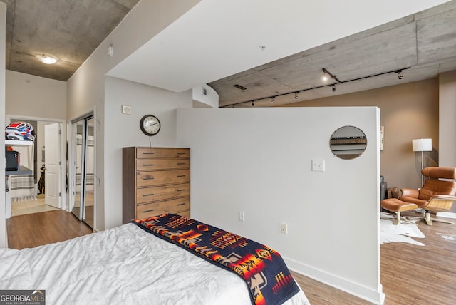 bedroom featuring rail lighting, light hardwood / wood-style floors, and ensuite bath