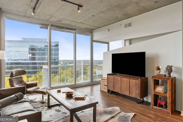 living room featuring dark hardwood / wood-style flooring, rail lighting, and a wall of windows