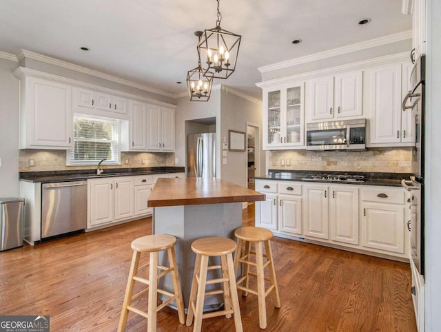 kitchen with light wood-type flooring, stainless steel appliances, white cabinets, and a kitchen island