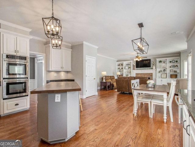 kitchen with pendant lighting, stainless steel double oven, white cabinets, and wood counters