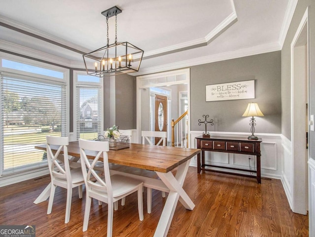 dining room with hardwood / wood-style flooring, crown molding, a raised ceiling, and a notable chandelier