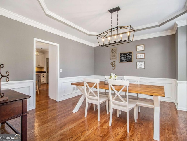 dining room featuring breakfast area, ornamental molding, wood-type flooring, and a tray ceiling