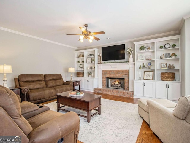 living room featuring crown molding, a fireplace, light hardwood / wood-style floors, and ceiling fan