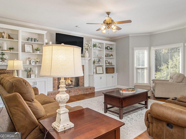 living room featuring a brick fireplace, crown molding, light hardwood / wood-style floors, and ceiling fan