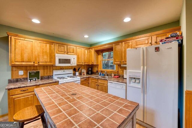 kitchen featuring white appliances, sink, tile counters, and a center island