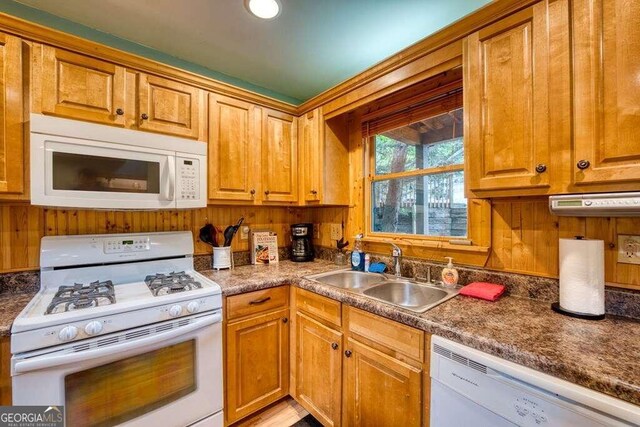 kitchen with wooden walls, white appliances, and sink