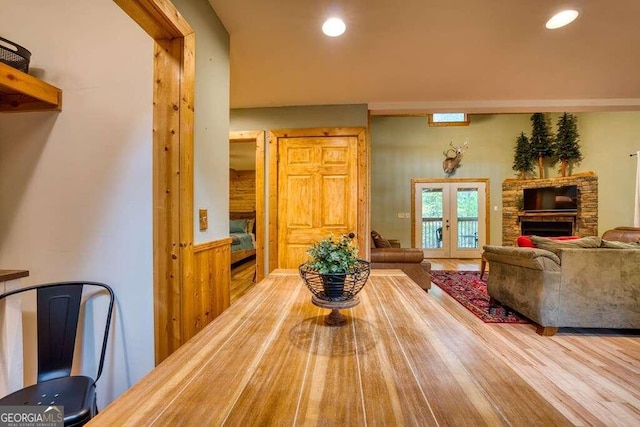 dining space with wood-type flooring, wooden walls, and french doors