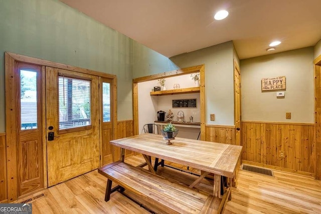 dining room featuring light hardwood / wood-style floors and wooden walls