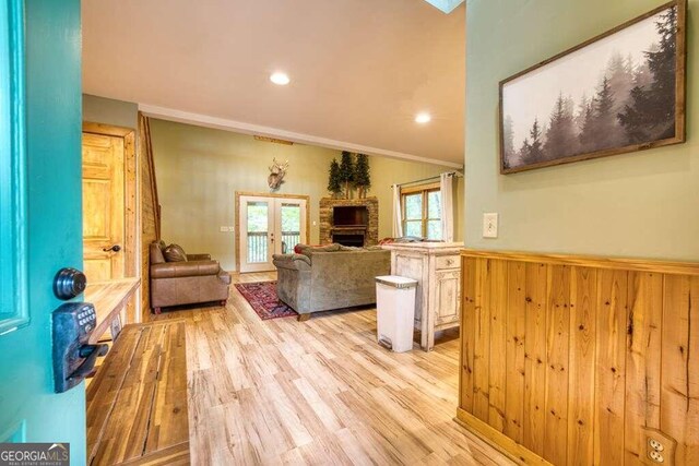 living room featuring wooden walls, french doors, light hardwood / wood-style floors, and crown molding