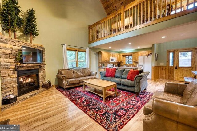 living room with a high ceiling, a healthy amount of sunlight, and light hardwood / wood-style flooring