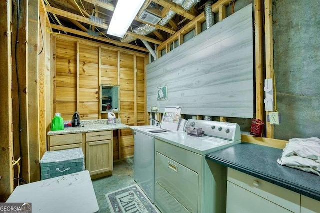 laundry room featuring wooden walls, cabinets, and washing machine and clothes dryer