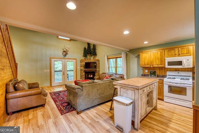 kitchen with a fireplace, white appliances, light wood-type flooring, and tile counters