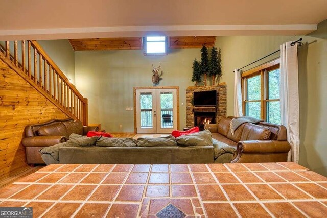 living room featuring a fireplace, a wealth of natural light, beamed ceiling, and french doors