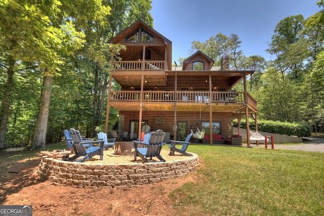 rear view of house featuring a lawn, a wooden deck, a patio, and an outdoor fire pit