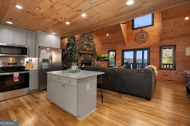 kitchen featuring light wood-type flooring, stainless steel appliances, lofted ceiling with beams, wooden ceiling, and a kitchen island