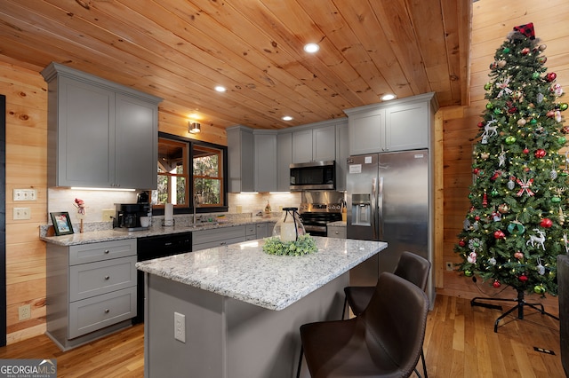 kitchen featuring appliances with stainless steel finishes, a center island, light hardwood / wood-style floors, and light stone counters