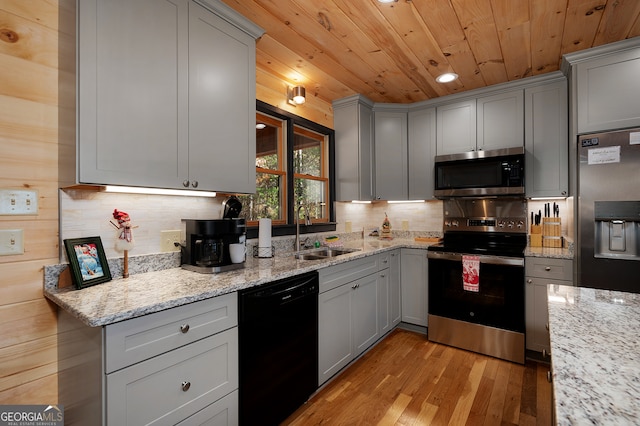 kitchen featuring sink, light stone counters, light hardwood / wood-style floors, gray cabinets, and appliances with stainless steel finishes