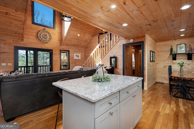 kitchen featuring white cabinets, light hardwood / wood-style floors, wood ceiling, and wooden walls