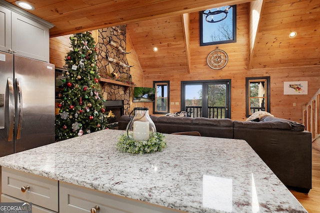 kitchen featuring a stone fireplace, light stone countertops, stainless steel refrigerator with ice dispenser, and light hardwood / wood-style flooring