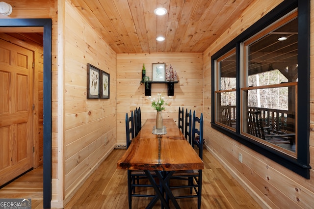 dining area with light hardwood / wood-style flooring, wood ceiling, and wood walls