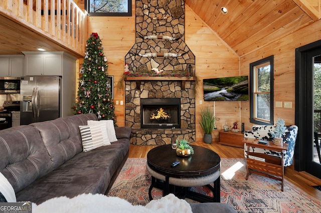 living room featuring a stone fireplace, high vaulted ceiling, wood walls, wood-type flooring, and wood ceiling