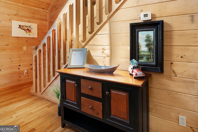 bar featuring dark brown cabinetry, light hardwood / wood-style floors, and wood walls