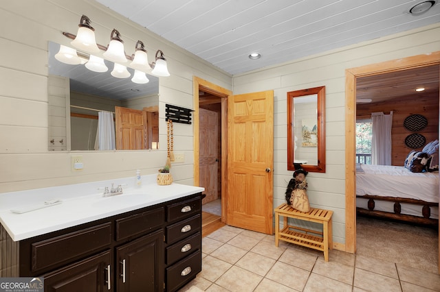 bathroom featuring tile patterned flooring, vanity, and wood walls