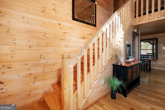 staircase featuring wood-type flooring and wood walls