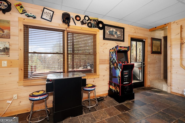 interior space featuring wooden walls and a drop ceiling