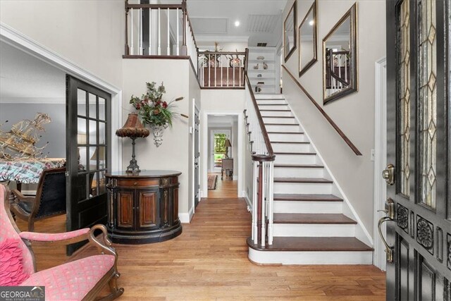 entryway with ornamental molding, french doors, light hardwood / wood-style flooring, and a high ceiling