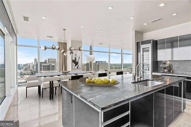 kitchen featuring dark stone counters, decorative backsplash, sink, and a large island