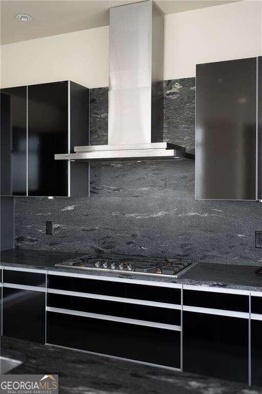 kitchen featuring stainless steel gas stovetop, wall chimney range hood, and tasteful backsplash