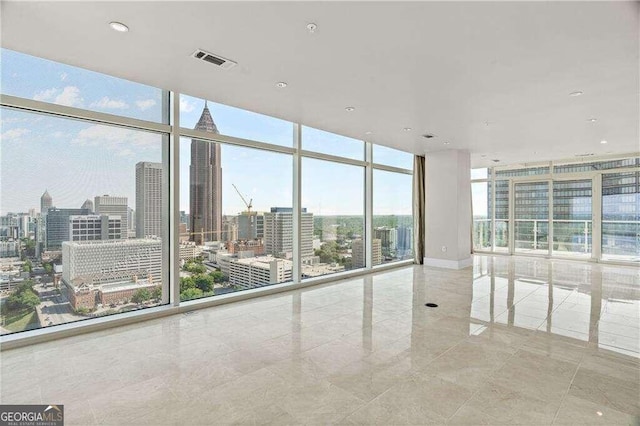 empty room featuring light tile patterned floors, expansive windows, and a healthy amount of sunlight