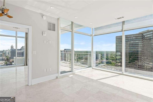 spare room featuring ceiling fan and expansive windows