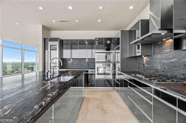 kitchen featuring stainless steel appliances, decorative backsplash, dark stone counters, and wall chimney range hood