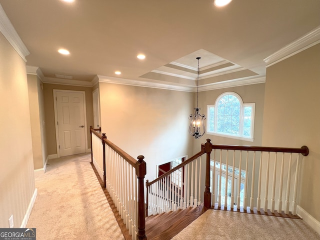 hall featuring a chandelier, light colored carpet, a raised ceiling, and ornamental molding