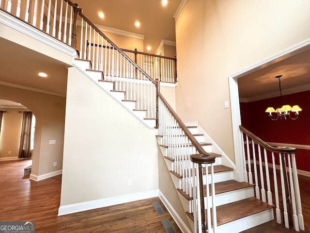 stairway with crown molding, hardwood / wood-style floors, and a chandelier