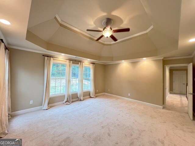 carpeted empty room featuring a tray ceiling, crown molding, and ceiling fan