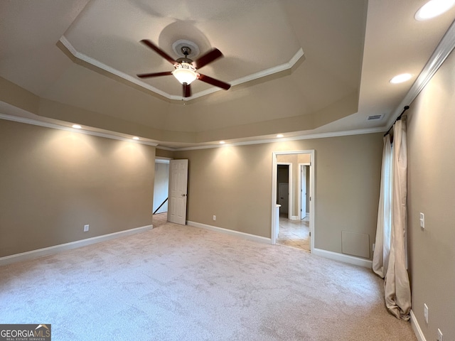 carpeted spare room featuring ceiling fan, a raised ceiling, and ornamental molding