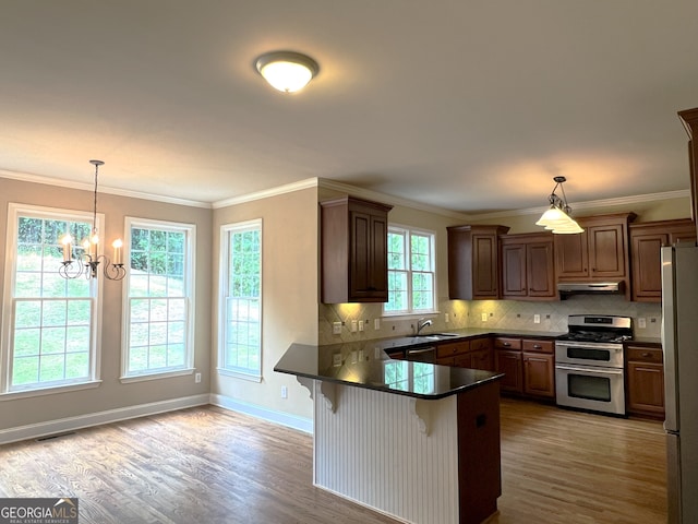 kitchen featuring hanging light fixtures, a notable chandelier, kitchen peninsula, a breakfast bar, and appliances with stainless steel finishes