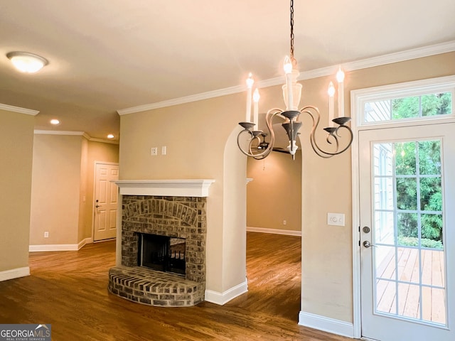 unfurnished living room featuring a fireplace, dark hardwood / wood-style floors, crown molding, and a notable chandelier