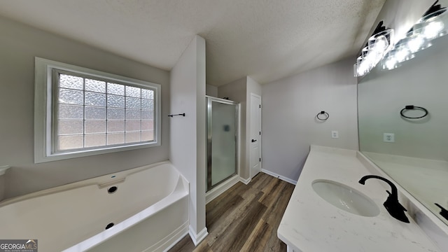 bathroom featuring plus walk in shower, vanity, a textured ceiling, and hardwood / wood-style flooring